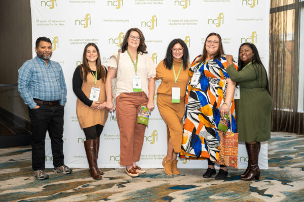 A group of attendees pose in front of an NCFL logo backdrop